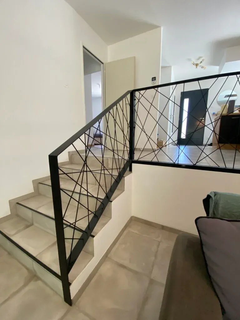 Garde-corps en acier thermolaqué noir à motifs croisés le long d'un escalier intérieur à Toulouse, fabrication sur mesure ManufactureVB