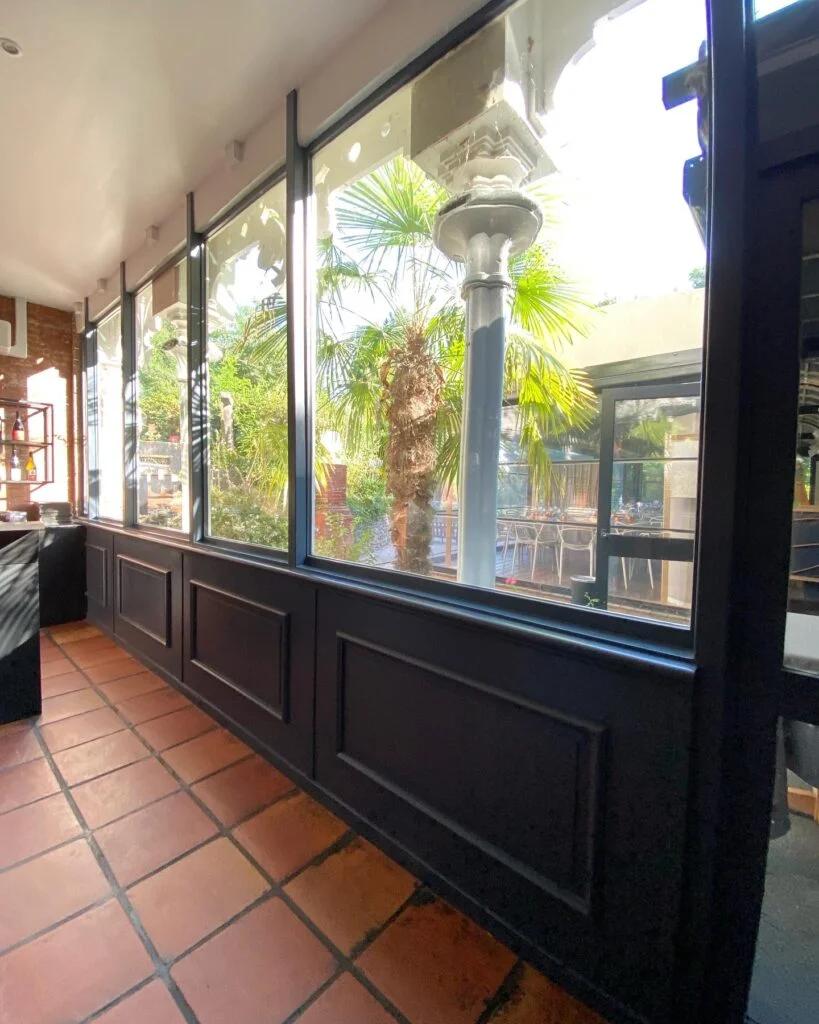 Verrière en métal noir et bois dans restaurant